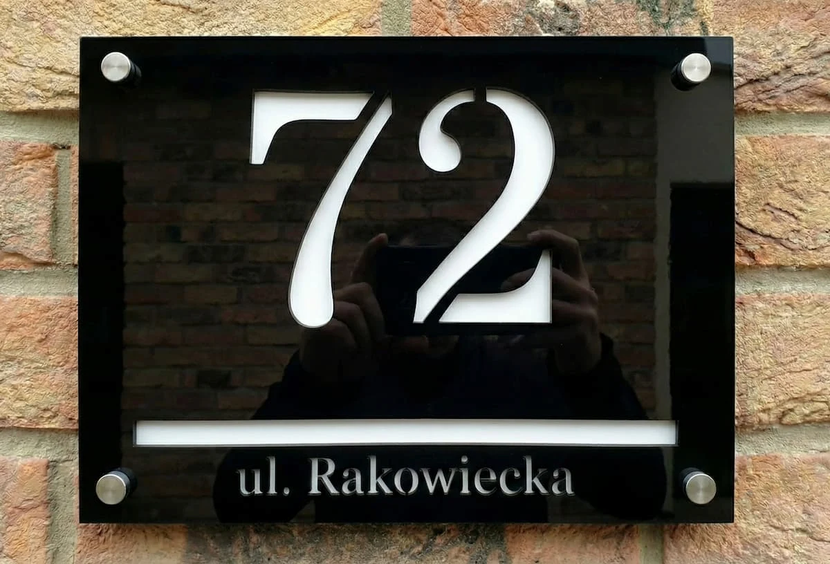 Czarna tabliczka z numerem posesji i białymi napisami Numeodesign